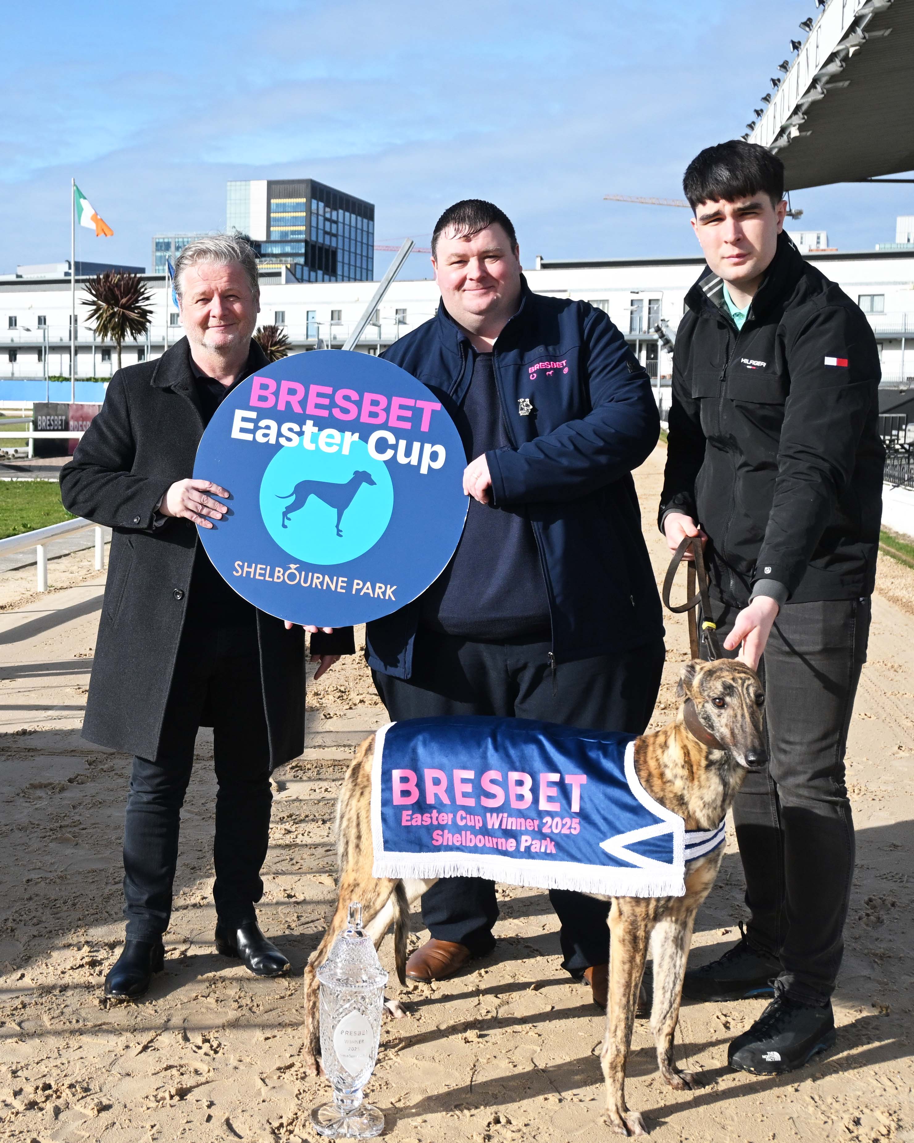 Carl Perry Head of Trading at BresBet hands over the trophy which will be awarded to the winner of the 2025 BresBet Easter Cup to Conor Matthews Racing Manager, Also included is Gary Purvis Social Media Manager BresBet.